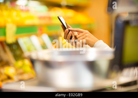 Die hand weibliche Nahaufnahme Handy Apfel orange Shop Stockfoto