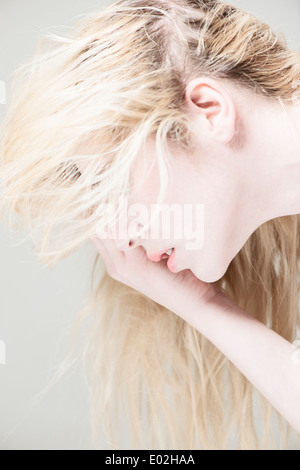 Seitenansicht des jungen schönen blonden Frau mit langen Haaren. Schauen unten, für Gesicht mit Hand. Stockfoto