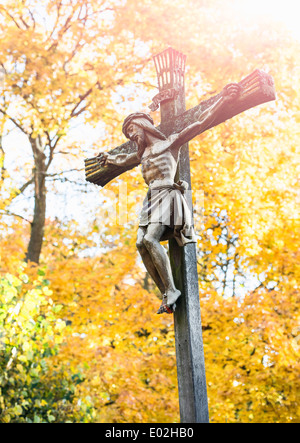 Jesus Christus am Kreuz mit Herbst Bäume im Hintergrund. Friedhof in Stockholm, Schweden. Stockfoto