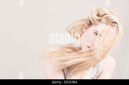 Junge schöne blonde Frau mit langen Haaren vor ihr Gesicht. Ausdruck von coole Haltung und Persönlichkeit zeigen. Stockfoto