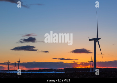 Windkraftanlagen Silhouette gegen einen feurigen Orange Sonnenuntergang mit Schnee auf dem Boden und einige Wolken am Himmel. Stockfoto