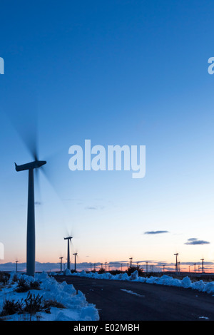 Wind Turbine Bewegung an einem kalten Wintertag bei Sonnenuntergang, mit Schnee auf dem Boden und ein fast klaren blauen Himmel. Stockfoto