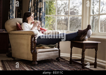 Eine junge Frau, die zu Hause mit ihren Füßen mit einer Tasse Tee entspannen. Stockfoto