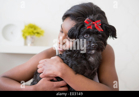 Ein junges Mädchen umarmt ihren kleinen schwarzen Hund. Stockfoto