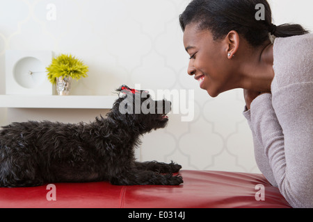 Ein junges Mädchen spielt mit ihren kleinen schwarzen Hund. Stockfoto