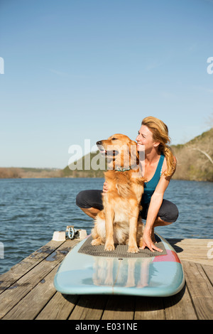 Eine Frau und ein Retriever Hund auf einem Paddleboard auf dem Steg. Stockfoto