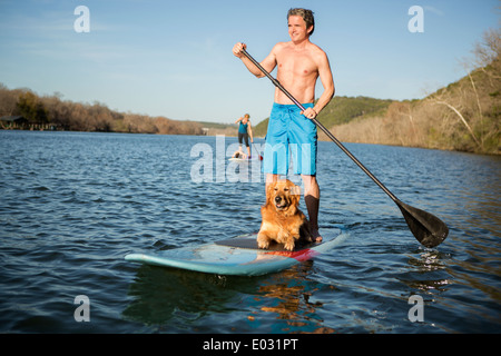 Ein Mann auf einem Paddleboard mit einem Hund. Stockfoto