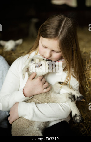 Ein Mädchen hält ein kleines Neugeborenes Lamm. Stockfoto