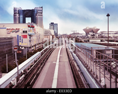 Neue Transit Yurikamome-Linie, die durch Odaiba, Tokio, Japan. Tokyo Big Sight und Telecom Center im Hintergrund. Stockfoto