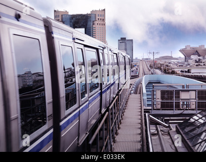 Neue Transit Yurikamome Zug durch Odaiba, Tokio, Japan. Tokyo Big Sight und Telecom Center im Hintergrund. Stockfoto