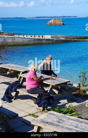 Prost, wenn Besucher einen Drink außerhalb des Turks Head Pub in St. Agnes, Isles of Scilly, Scillies, Cornwall UK im April genießen Stockfoto