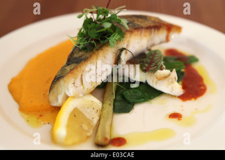 Eine moderne estnische Mahlzeit gebratener Fisch mit grünem Gemüse und eine Creme Karotte Sauce serviert. Stockfoto