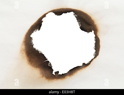 Stück Papier mit verbrannten Loch in Kreisform mit weißem Hintergrund. Stockfoto