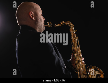 Erwachsenen Musiker spielt Tenorsaxophon, dunkler Hintergrund Stockfoto