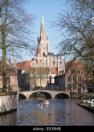 Ein Blick von Begijnhof, Brügge, Belgien, in Richtung der Liebfrauenkirche mit Touristenboot nähert sich Stockfoto