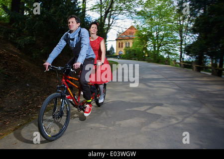 Junges Wwoman paar und Mann mit dem Tandem-Fahrrad Radfahren im park Stockfoto