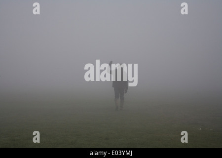 Mann mit Mütze und Wellington boots zu Fuß in Feld an nebeligen Tag Stockfoto