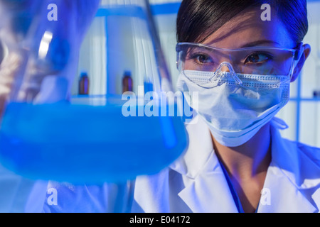 Eine chinesische asiatische Frauen Arzt oder wissenschaftlicher Mitarbeiter oder Arzt eine Flasche blaue Flüssigkeit in einem Labor zu betrachten. Stockfoto