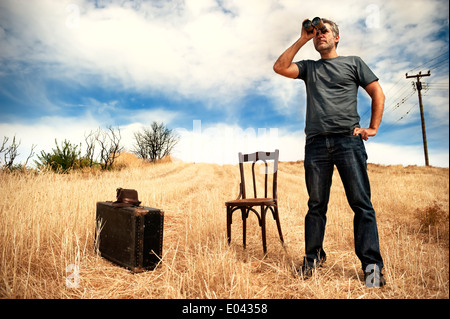 Mann mit dem Fernglas in einem Feld stehen Stockfoto