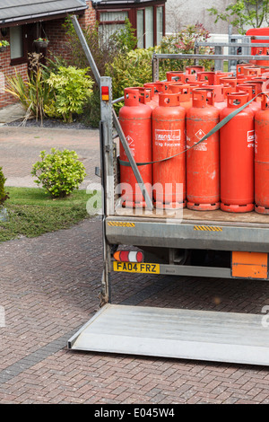 UK, Großbritannien. Eine Lieferung von Haushalt rote Calor Gasflaschen auf der Rückseite einen Pickup-Truck vor einem Haus. Stockfoto