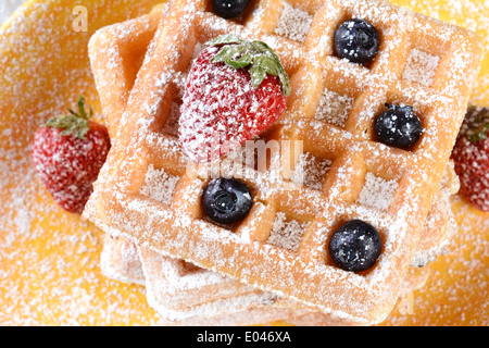 Nahaufnahme von fruchtigen Waffeln mit Puderzucker bedeckt. Frische Heidelbeeren und Erdbeeren auf einen Stapel von belgischen Stil Waffeln Stockfoto