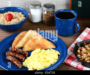 Landhausstil Rührei Ei-Frühstück auf einem rustikalen hölzernen Restauranttisch. Eiern, Würstchen, toast Stockfoto