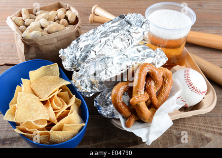 Nahaufnahme von einem Tablett mit Essen und Souvenirs, die man bei einem Baseballspiel finden würde. Elemente enthalten, Hot Dogs in Folie verpackt Stockfoto