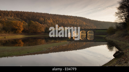 Malerischer Blick auf sonnenbeschienene Bögen der Brücke & Wald, in ruhigem Wasser von Lindley Holz Behälter wider - in der Nähe von Otley, North Yorkshire, England, UK. Stockfoto