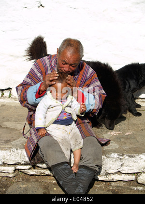 Ein bhutanischer Großvater hält sein Enkel im Kichu Kloster in Paro, Bhutan Stockfoto