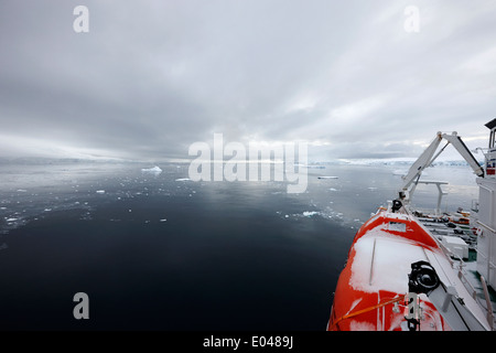 Expeditionsschiff mit Rettungsboot schneebedeckt im Fournier Bay auf Anvers Island Antarktis festgemacht Stockfoto