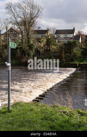 Öffentlichen Fußweg Zeichen, zu teilweise überdachte Trittsteine Kreuzung fließenden Fluss-River Wharfe in der Nähe von Skipton, West Yorkshire, England, UK. Stockfoto