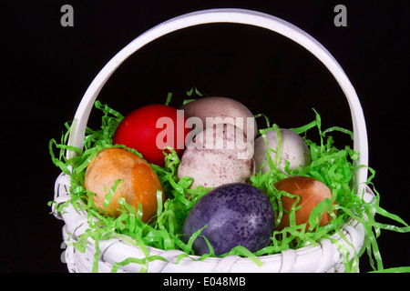 Weißen geflochtenen Korb gefüllt mit vielfarbigen Ostereier Stockfoto