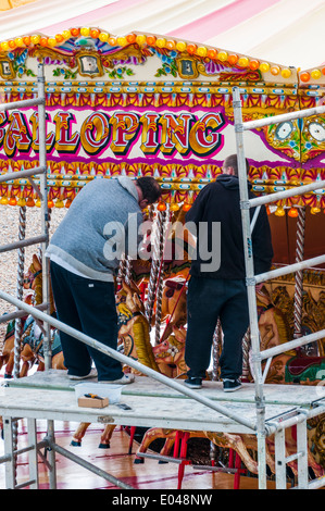 Zwei Männer stehen auf einem Gerüst Turm ersetzen Glühbirnen auf einem Jahrmarkt Karussell am Strand von Brighton Stockfoto