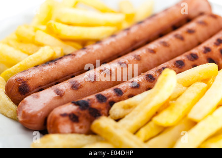 drei leckere Würstel auf einem weißen Teller mit Pommes frites Stockfoto