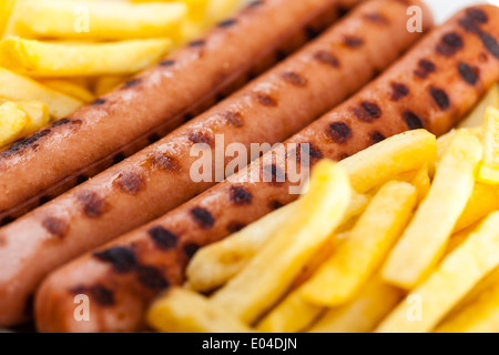 drei leckere Würstel auf einem weißen Teller mit Pommes frites Stockfoto