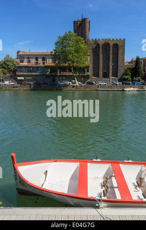 Ein kleines Boot festgemacht am Fluss Hérault übersehen von Agde Kathedrale in der Stadt Agde, Herault, Languedoc-Roussillon, Frankreich Stockfoto