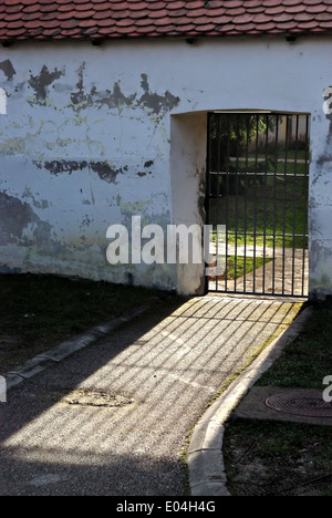 Grilltür auf einer weißen Mauer von der Sonne beleuchtet. Stockfoto