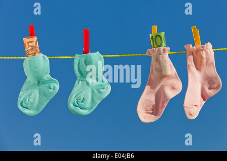 Baby Socken auf der Wäscheleine mit Eurobank Noten. Blauer Himmel., Baby Socken Auf Waescheleine Mit Eurogeldscheinen. Blauer Himmel. Stockfoto