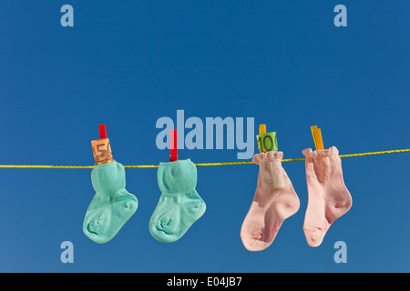 Baby Socken auf der Wäscheleine mit Eurobank Noten. Blauer Himmel., Baby Socken Auf Waescheleine Mit Eurogeldscheinen. Blauer Himmel. Stockfoto