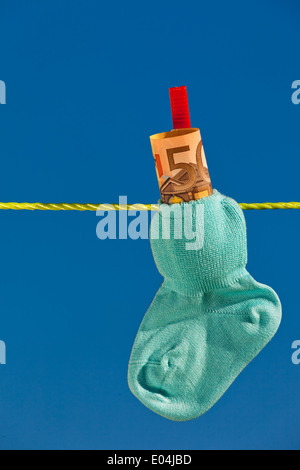 Baby Socken auf der Wäscheleine mit Eurobank Noten. Blauer Himmel., Baby Socken Auf Waescheleine Mit Eurogeldscheinen. Blauer Himmel. Stockfoto