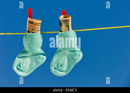 Baby Socken auf der Wäscheleine mit Yen Banknoten aus Japan., Baby Socken Auf Waescheleine Mit Yen Geldscheinen aus Japan. Stockfoto