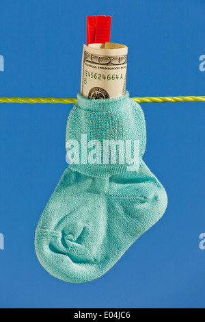 Baby Socken auf der Wäscheleine zu den trockenen. Blauer Himmel. mit Dollar Geld in Bar Stockfoto