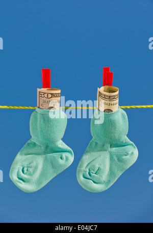 Baby Socken auf der Wäscheleine zu den trockenen. Blauer Himmel. mit Dollar Geld in Bar Stockfoto