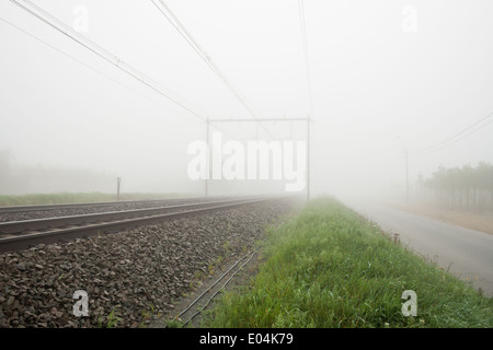 hängt einen dichten Nebel entlang der Straße und Schiene Stockfoto