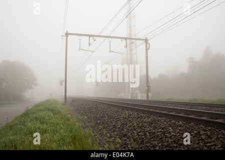 hängt einen dichten Nebel entlang der Straße und Schiene Stockfoto