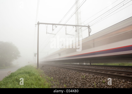 hängt einen dichten Nebel an der Straße und Bahn ein Zug vorbei Stockfoto