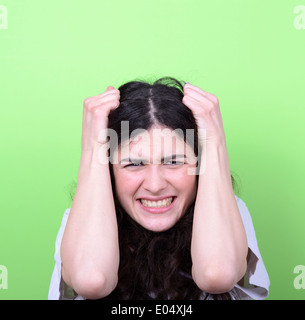 Porträt von böse Mädchen ziehen Haare vor grünem Hintergrund Stockfoto