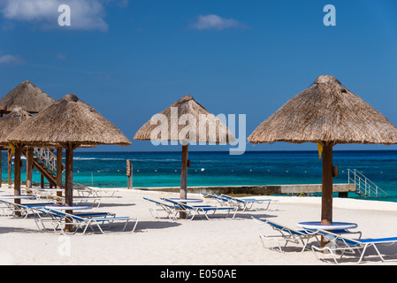 Strohgedeckte Sonnenschirme und liegen in einem Luxusresort. Cozumel, Mexiko. Stockfoto