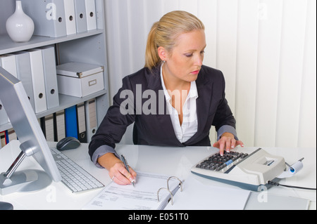 Buchhalterin bei der Arbeit im Büro mit Taschenrechner, Eine Buchhalterin Bei der Arbeit Im Buero Mit Taschenrechner Stockfoto