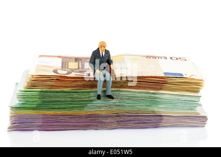 Symbolische Foto für den Ruhestand und die Altersvorsorge, Figur eines alten Mannes sitzt auf einem Haufen von Banknoten, Symbolfoto für Stockfoto